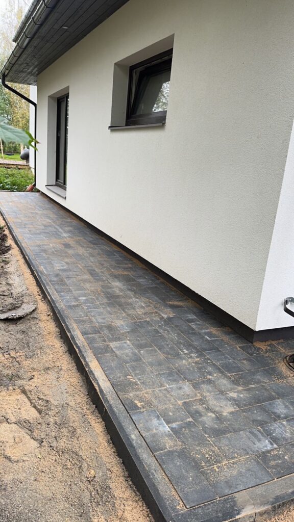 Antratsiitne tänavakivi kõnnitee maja kõrval Harjumaal - tumehall kivisillutis äärekiviga